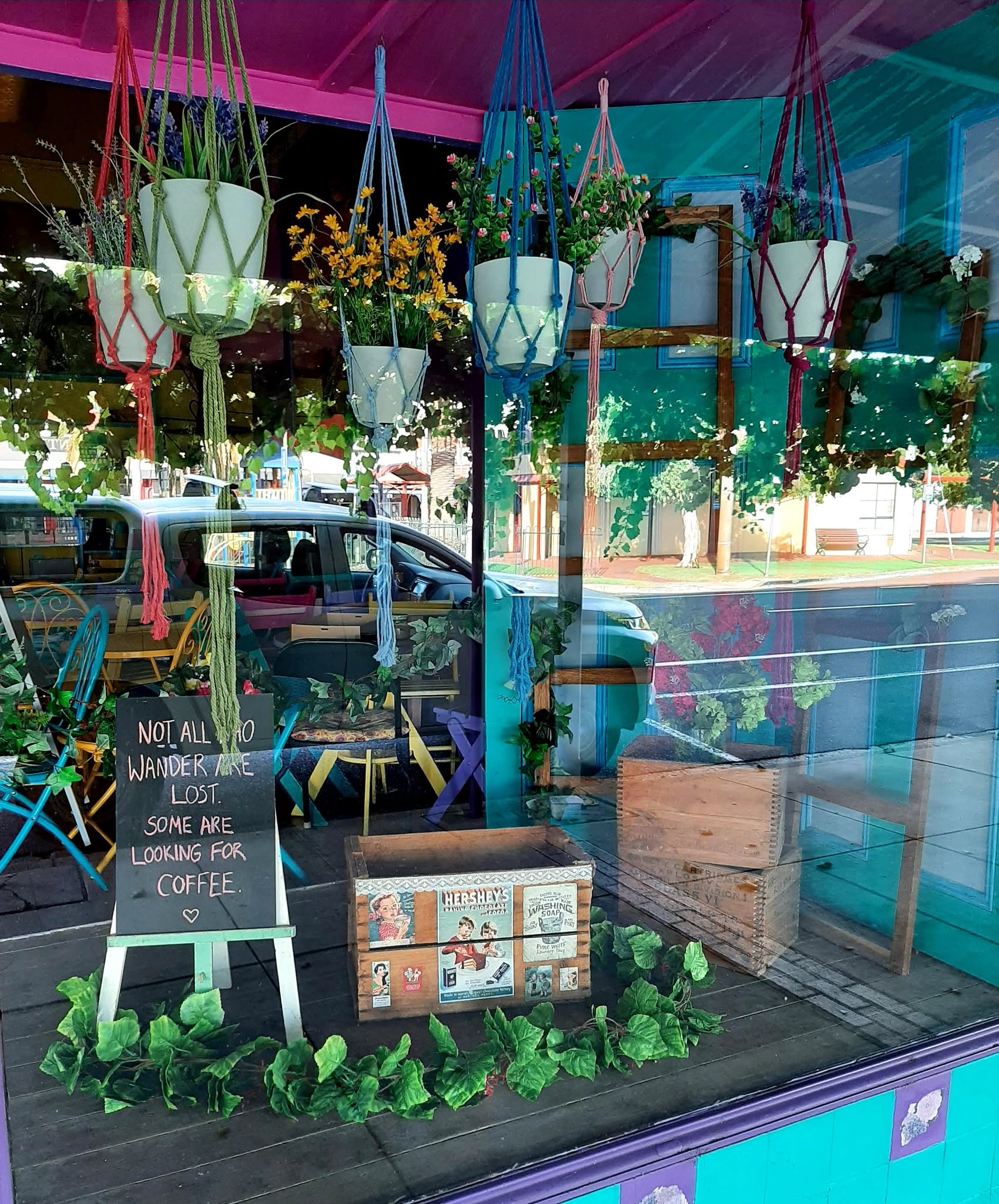 The front window hung with plant baskets and a chalkboard about coffee