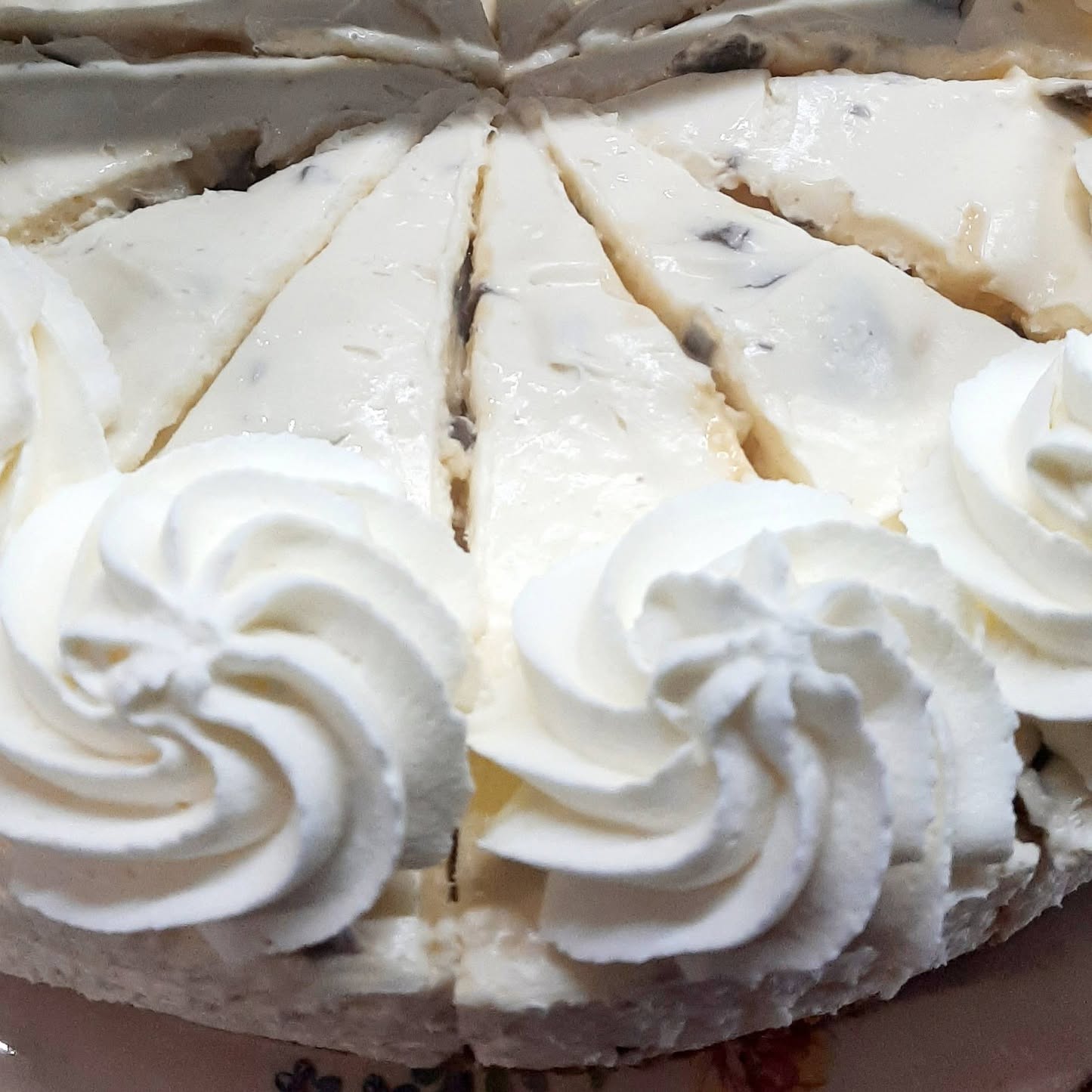 A sliced cheesecake topped with whipped cream