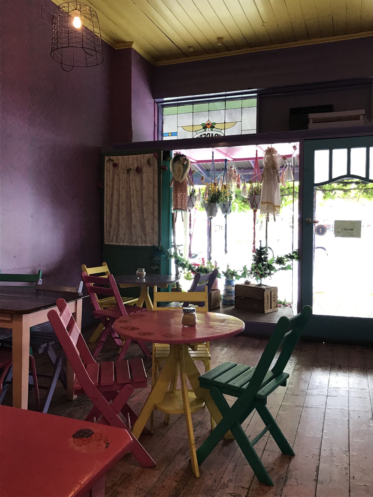 Inside the cafe looking out the front door, with red and green chairs and a round red table