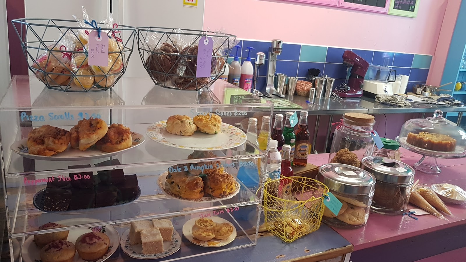 Baskets of biscuits and stands of scones and slices on the pink counter